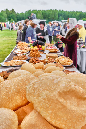 Tobolsk, Russia - July 20, 2024: Traditional treats of Siberian Tatar on feast table. In foreground national baked goods round baursaks. Tatar Gastronomic Festivalのeditorial素材