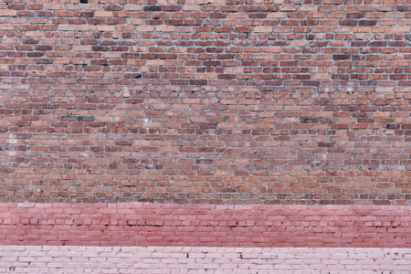 Red brick wall texture as abstract background. Old shabby dirty surface with painted pink stripes at...