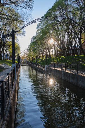 Motovilikh River with concrete banks in park garden at sunset. Landscape in city park in spring. Perm, Russiaの写真素材