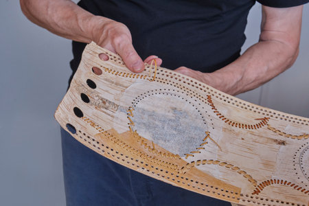 Hands of senior male craftsman decorate a blank of product made of birch bark. Handmade conceptの写真素材