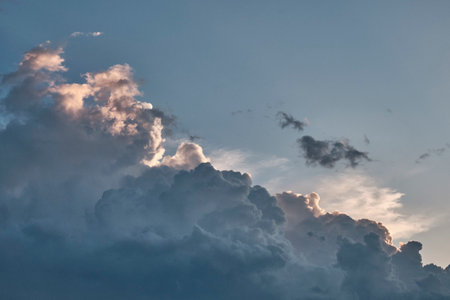 Stunning sky filled with towering cumulus clouds, illuminated by soft glow of sun. Contrast between light and shadow creates dramatic and atmospheric scene.の写真素材