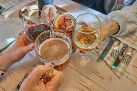 Group of female senior friends toasting with a variety of drinks, including beer, red and white...