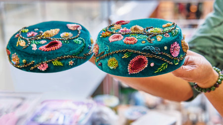Womans hands holding two handcrafted Tatar skullcap with intricate floral bead embroidery, showcasing fine craftsmanship and cultural artistry.の写真素材