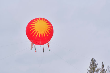 Bright red and yellow circular ornament with sunburst design, suspended in the sky as festive decoration for traditional Slavic Maslenitsa celebration. Copy spaceの写真素材
