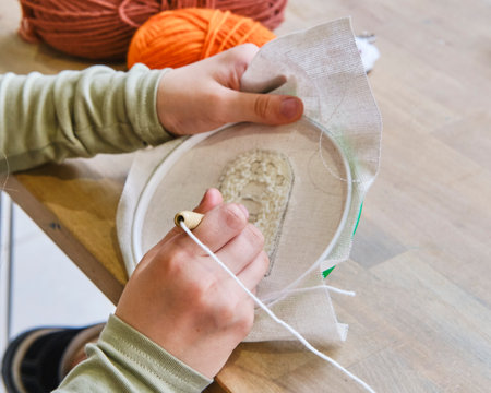 Close-up of child's hands using round hoop and punch needle for embroidery on fabric.の写真素材