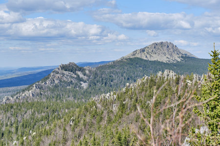 Scenic view of rugged mountain peaks and dense coniferous forest in Taganay National Park, Southern Urals, Russia. Natural landscape with rocky formations. Mitkiny Rocks and Otkliknoy Ridge Rockの写真素材