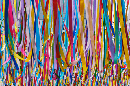Bright multicolored ribbons hanging vertically as a decorative installation, creating a vibrant and...