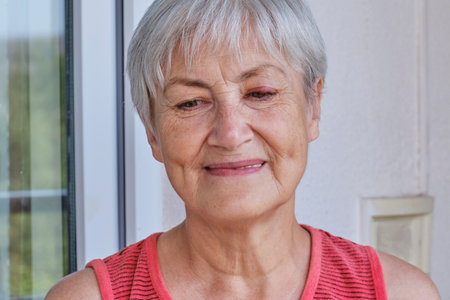 Close-up portrait of senior woman with short gray hair and stye on eye. Stye or hordeolum is...