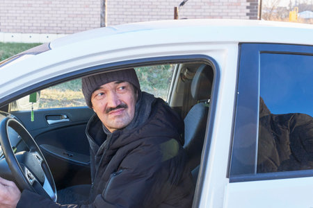 Close-up portrait of man with mustache, wearing dark jacket and knitted cap, looking over his...