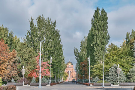 Volgograd, Russia - October 6, 2025: Scenic view of majestic orthodox cathedral with golden domes, viewed through an Alley of Heroes by tall green and autumn trees in Volgograd, Russiaのeditorial素材