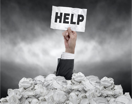 Businessman need help under crumpled paperの写真素材