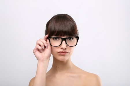 Funny expression. A beautiful woman with a funny expression wearing glasses on a pink background.の写真素材