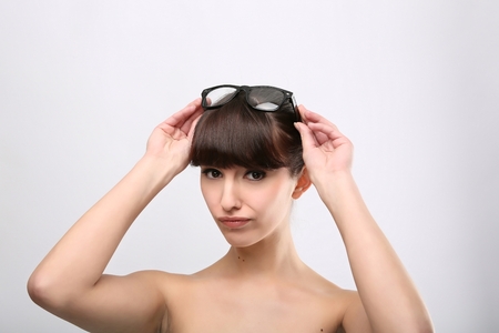 Funny expression. A beautiful woman with a funny expression wearing glasses on a pink background.の写真素材