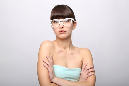 Funny expression. A beautiful woman with a funny expression wearing glasses on a pink background.の写真素材