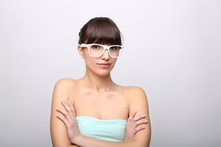 Funny expression. A beautiful woman with a funny expression wearing glasses on a pink background.の写真素材