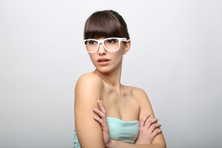 Funny expression. A beautiful woman with a funny expression wearing glasses on a pink background.の写真素材