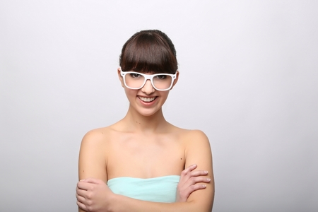 Funny expression. A beautiful woman with a funny expression wearing glasses on a pink background.の写真素材