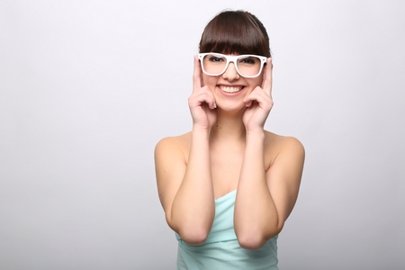 Funny expression. A beautiful woman with a funny expression wearing glasses on a pink background.の写真素材