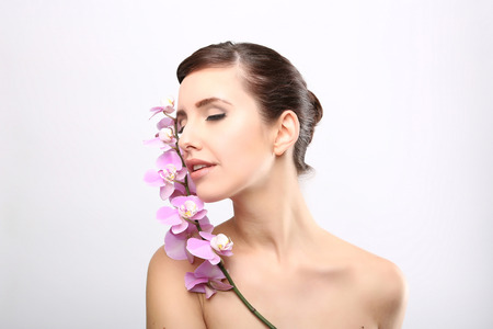 Beautiful Girl With Orchid Flowers.Beauty Model Woman Face. Perfect Skin. Professional Make-up.Makeup. Fashion Artの写真素材