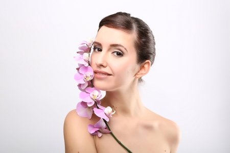 Beautiful Girl With Orchid Flowers.Beauty Model Woman Face. Perfect Skin. Professional Make-up.Makeup. Fashion Artの写真素材