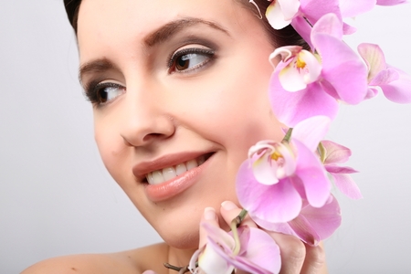 Beautiful Girl With Orchid Flowers.Beauty Model Woman Face. Perfect Skin. Professional Make-up.Makeup. Fashion Artの写真素材