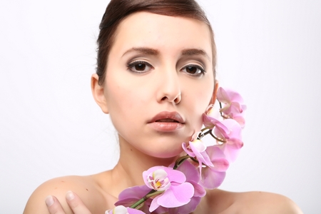 Beautiful Girl With Orchid Flowers.Beauty Model Woman Face. Perfect Skin. Professional Make-up.Makeup. Fashion Artの写真素材