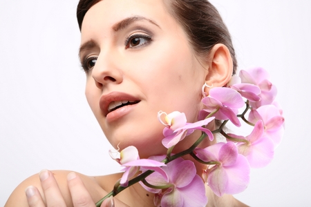 Beautiful Girl With Orchid Flowers.Beauty Model Woman Face. Perfect Skin. Professional Make-up.Makeup. Fashion Artの写真素材