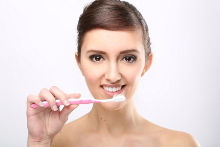 Closeup of beautiful young lady holding toothbrush and smilingの写真素材