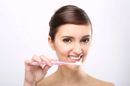 Closeup of beautiful young lady holding toothbrush and smilingの写真素材