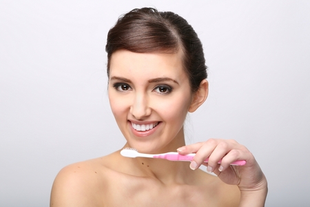 Closeup of beautiful young lady holding toothbrush and smilingの写真素材