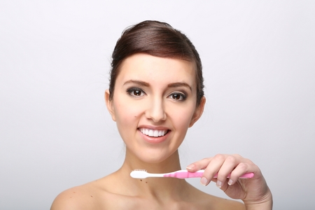Closeup of beautiful young lady holding toothbrush and smilingの写真素材