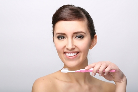 Closeup of beautiful young lady holding toothbrush and smilingの写真素材