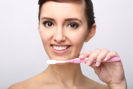 Closeup of beautiful young lady holding toothbrush and smilingの写真素材
