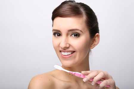 Closeup of beautiful young lady holding toothbrush and smilingの写真素材