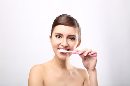 Closeup of beautiful young lady holding toothbrush and smilingの写真素材