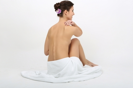 Portrait of a beautiful lady covering herself with a white towel, isolated on whiteの写真素材