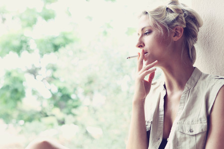 a beautiful girl smokes on the verandaの写真素材