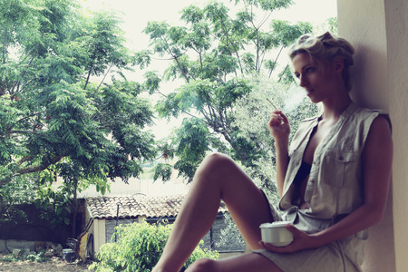 a beautiful girl smokes on the verandaの写真素材