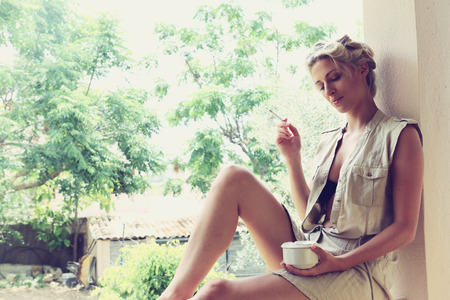 a beautiful girl smokes on the verandaの写真素材