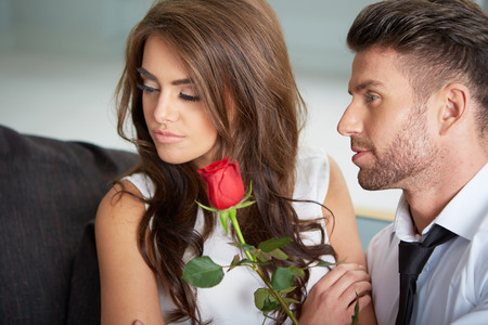 Portrait of two young people looking at each other and holding a roseの写真素材