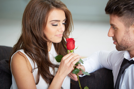 Portrait of two young people looking at each other and holding a roseの写真素材