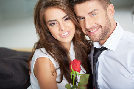 Portrait of two young people looking at each other and holding a roseの写真素材