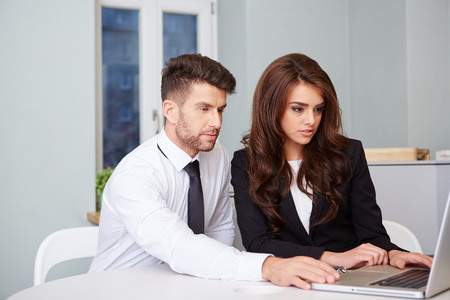Portrait of executive employees looking at laptop monitor and discussing new projectの写真素材