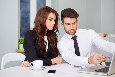 Portrait of executive employees looking at laptop monitor and discussing new projectの写真素材