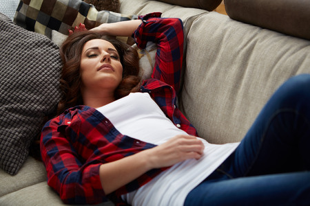 Closeup of a smiling young woman lying on couchの写真素材
