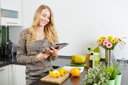 Blonde woman using a tablet computer to cook in her kitchenの写真素材