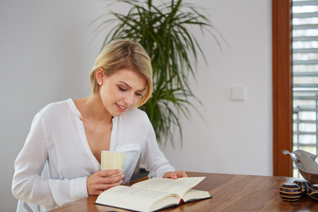 Beautiful woman reading a book at a tableの写真素材