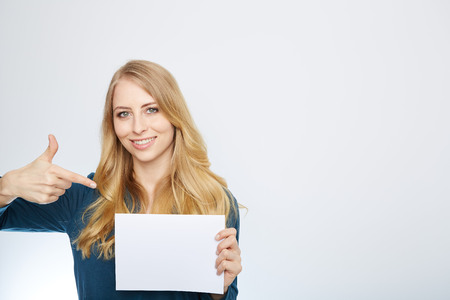 Happy smiling young business woman showing blank signboard, isolated over white backgroundの写真素材