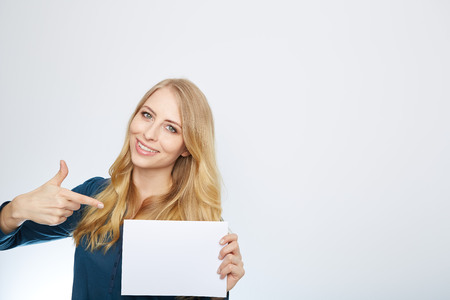 Happy smiling young business woman showing blank signboard, isolated over white backgroundの写真素材