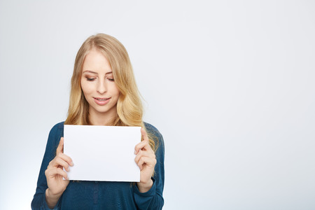 Happy smiling young business woman showing blank signboard, isolated over white backgroundの写真素材